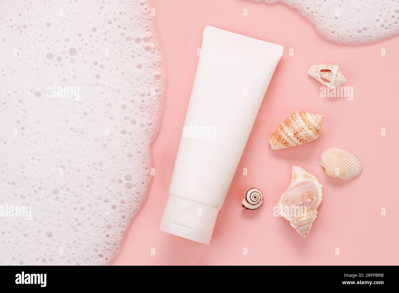 cosmetic cream tube, soap foam, bubbles, sea shells on pink background ...