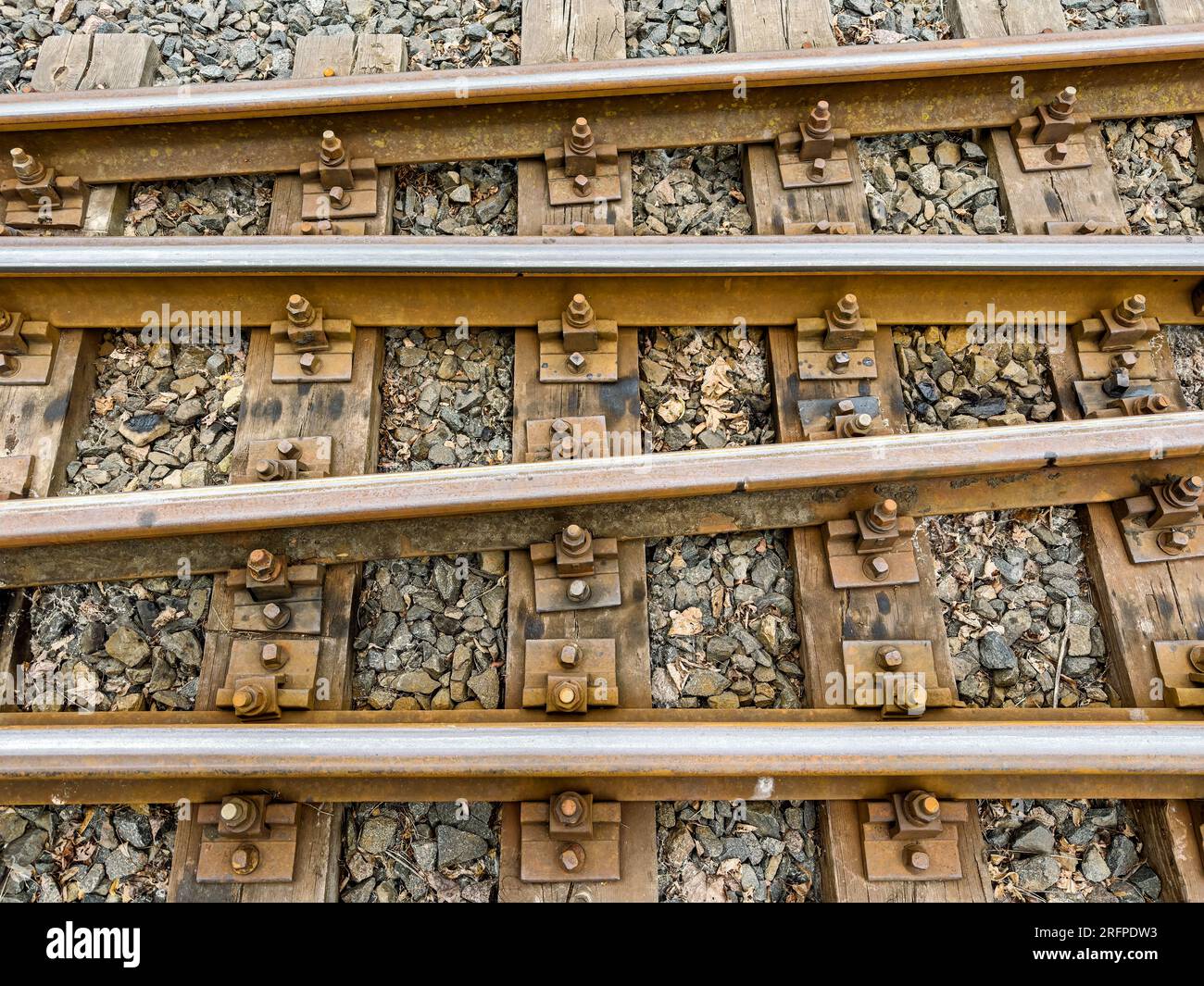 narrow gauge railway with thresholds, gravel and rusty bolts. transportation background. Stock Photo