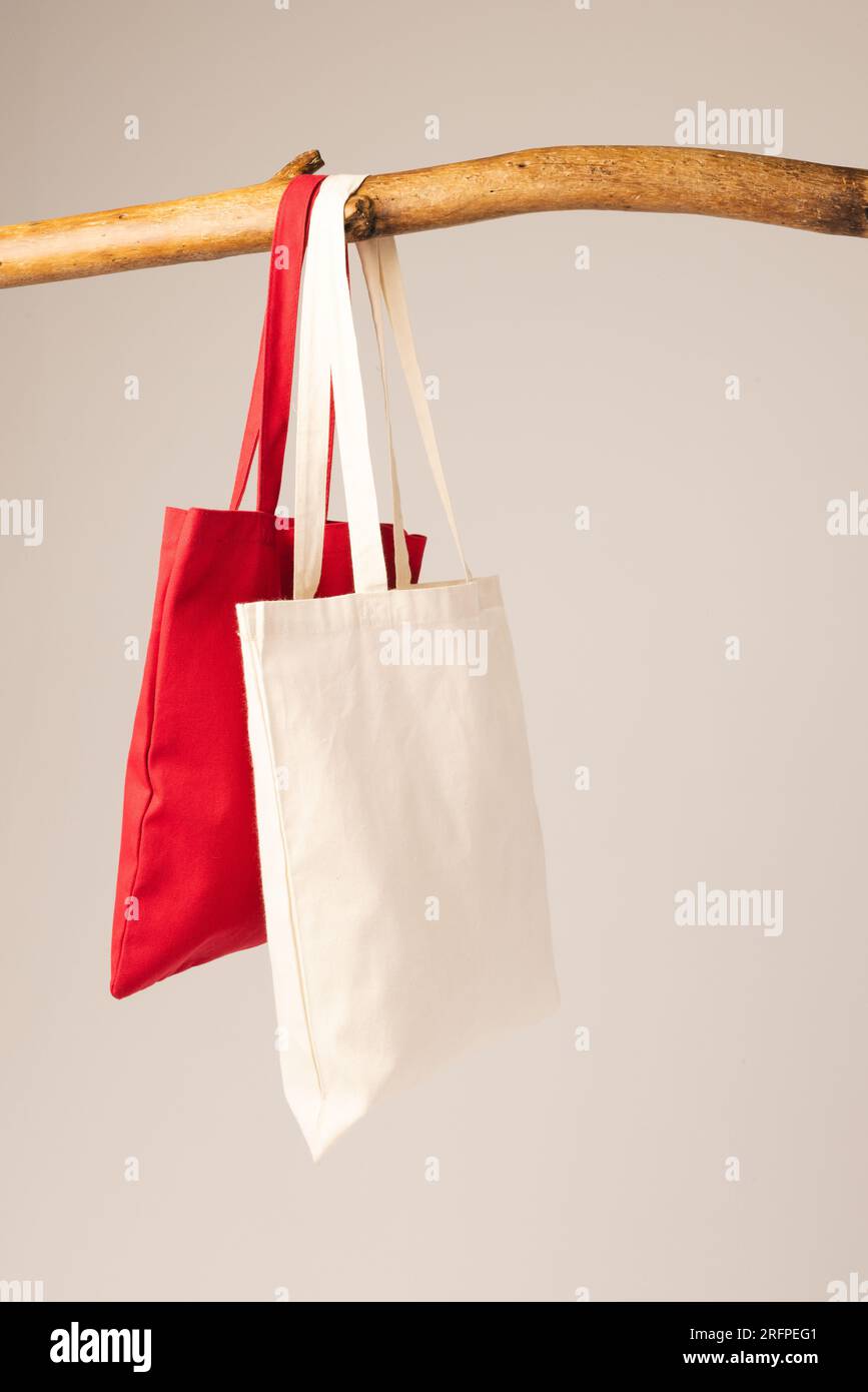 White and red canvas bags hanging from wooden branch with copy space on