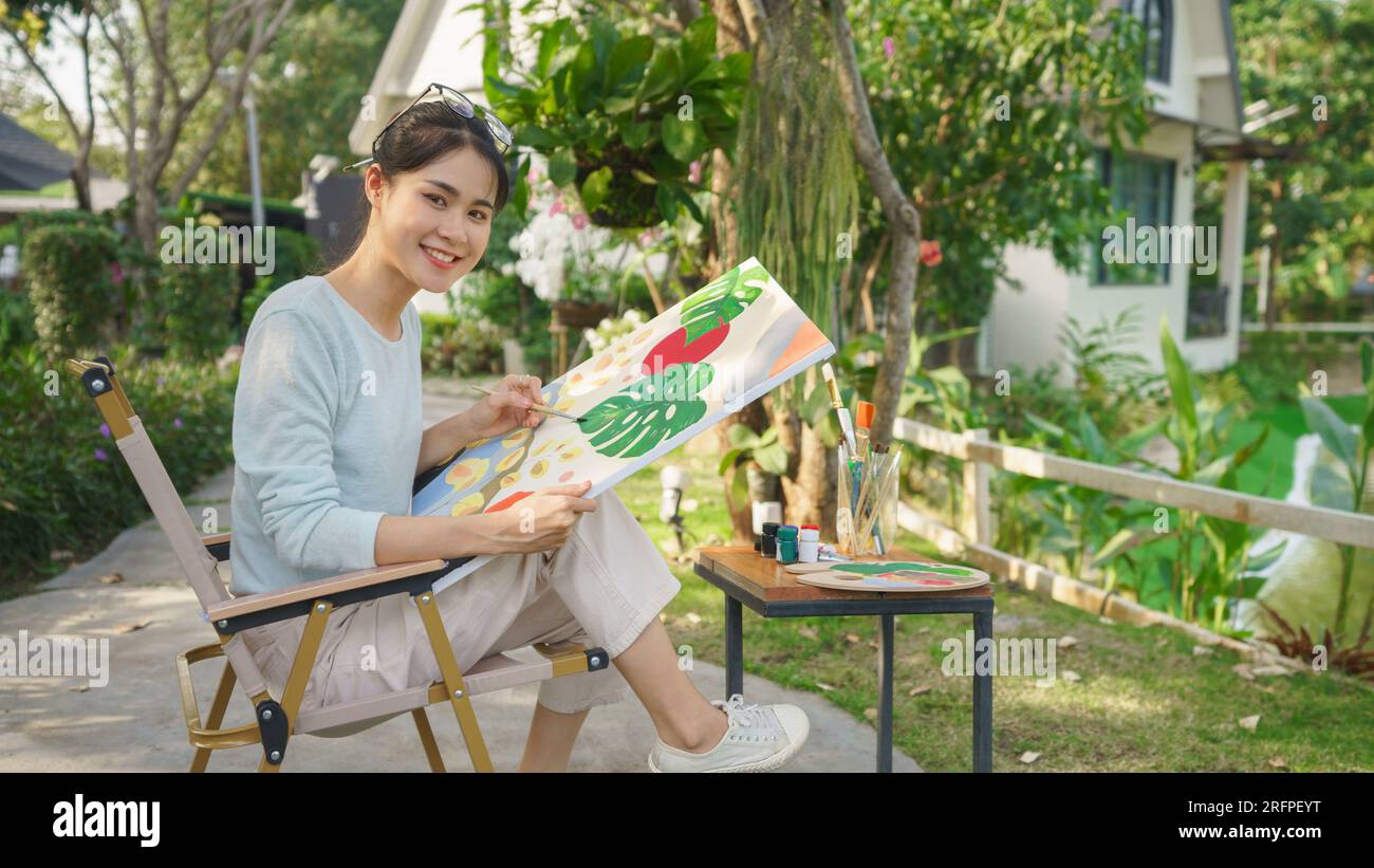 Outdoor activity concept, Female artist sits in park and painting ...