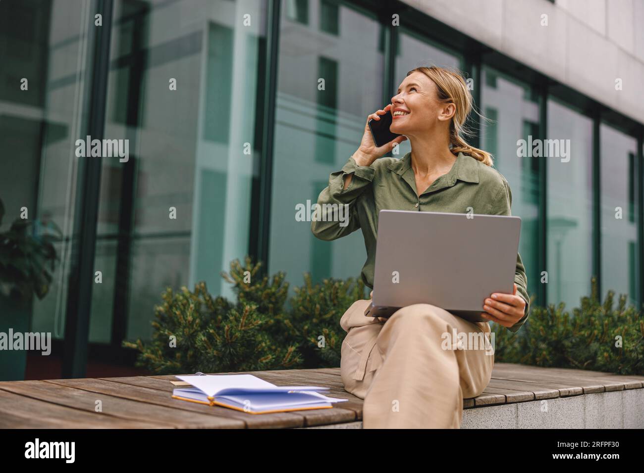Smiling woman manager talking with client and work on modern building background Stock Photo
