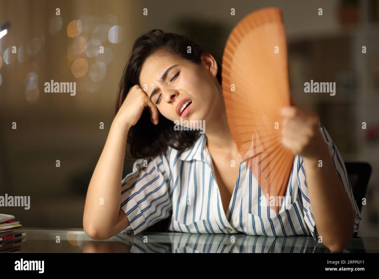 Overwhelmed woman suffering heat stroke fanning at home in the night Stock Photo