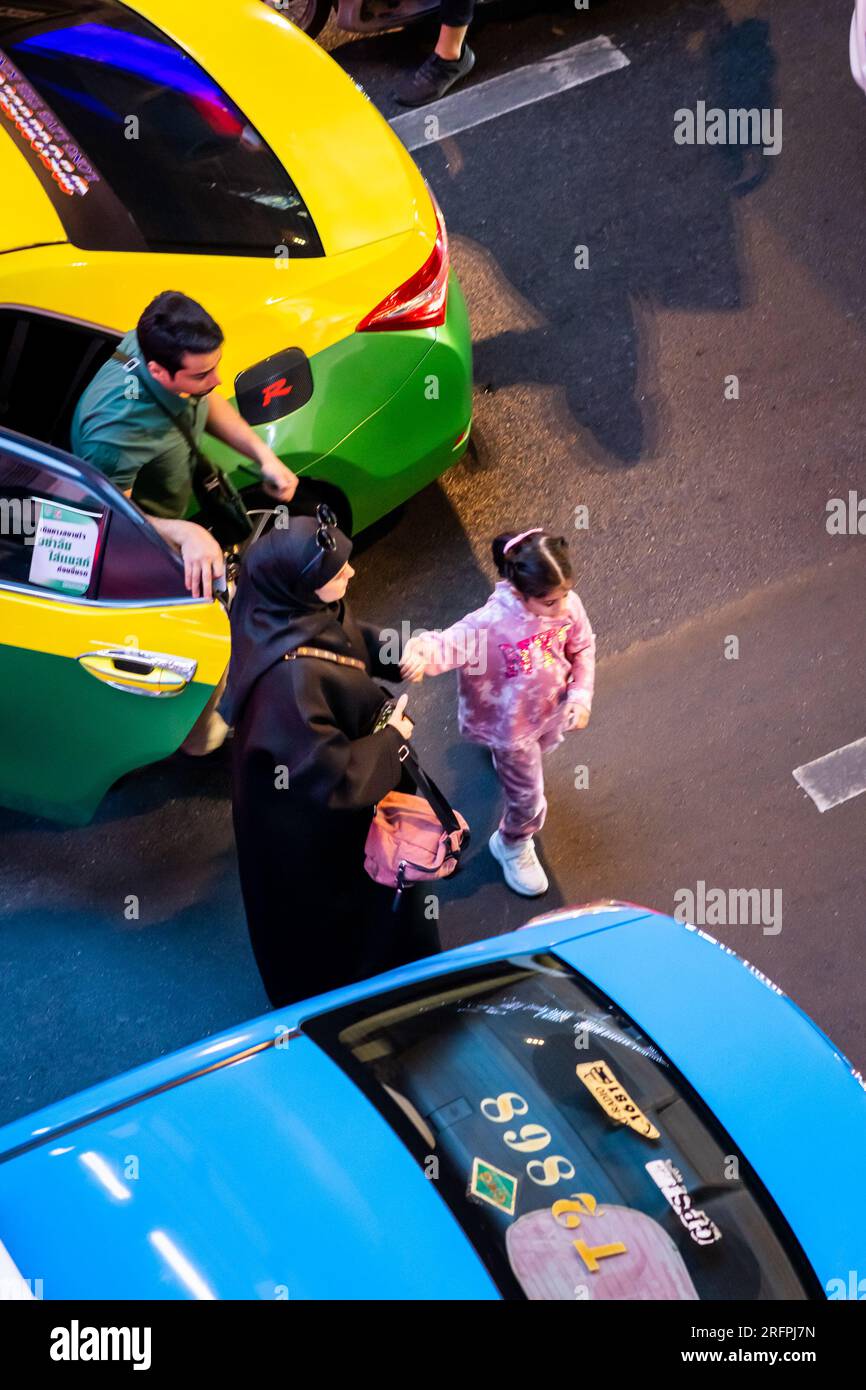 A Muslim family exit a taxi in the busy Bangkok city traffic on Sukhumvit Rd. in the Siam area of Bangkok City, Thailand. Stock Photo