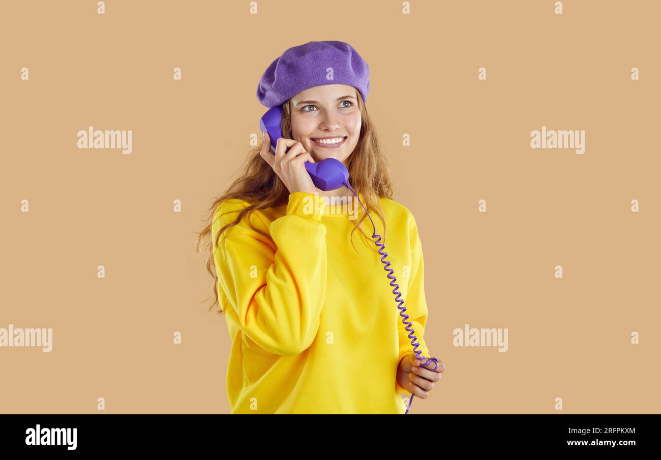 Girl in grandmothers beret with receiver of old wired telephone. Stock Photo