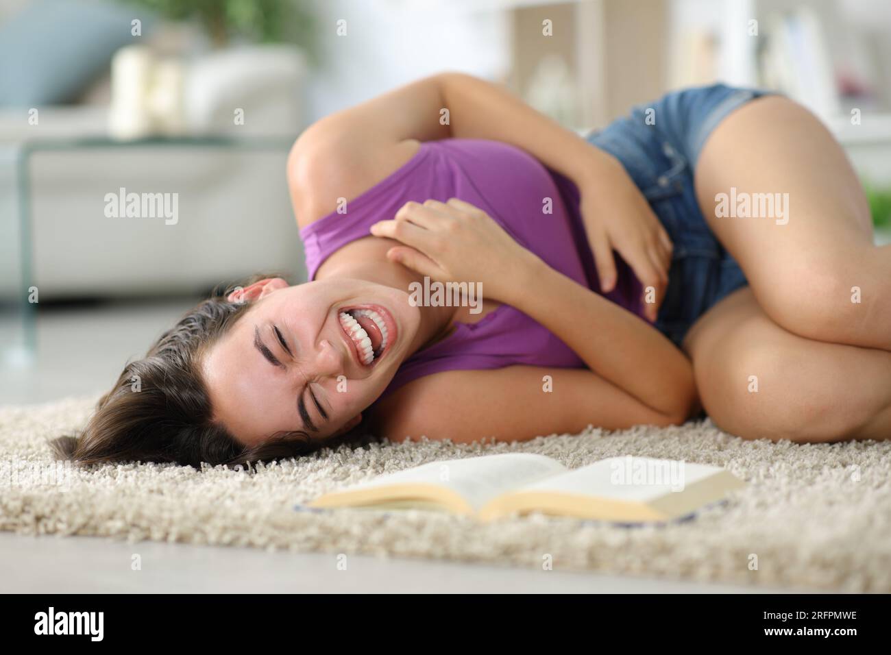 Happy woman laughing hilarious alone lying on a carpet at home Stock Photo