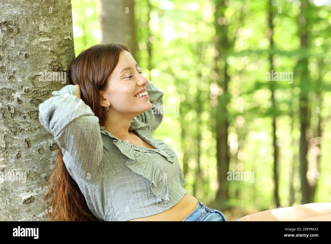 Happy woman resting alone sitting in a green forest Stock Photo