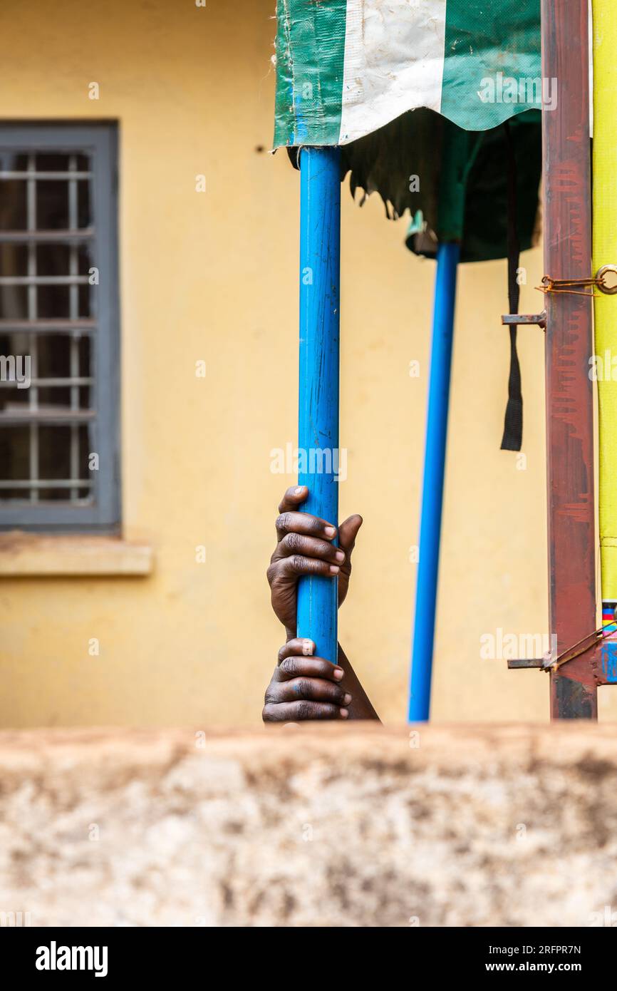 Two black man's hands tightly gripping a blue pole. Jinja, Uganda. Stock Photo