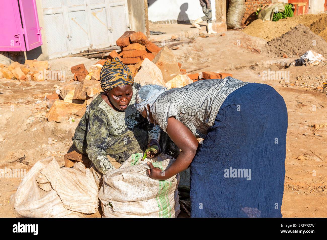 At Jinja market: two ladies discussing the contents of a large sack of fruit. Stock Photo