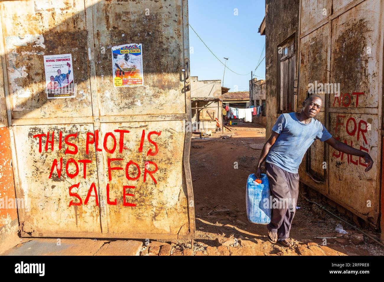 Man carrying a heavy can, exiting a property marked "this plot is not