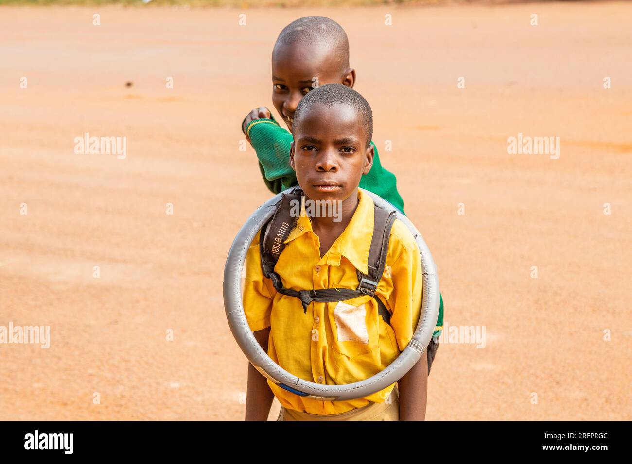 Two kids posing, one wearing a steering wheel cover around his neck. Jinja, Uganda. Stock Photo