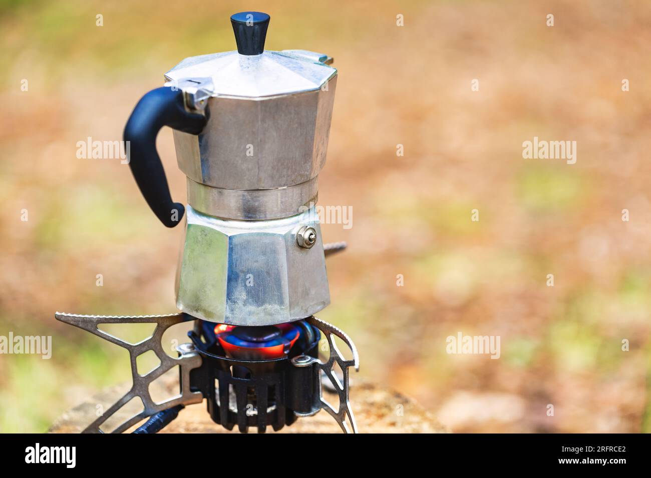 https://c8.alamy.com/comp/2RFRCE2/brewing-italian-style-coffee-in-aluminum-moka-pot-on-a-portable-stove-during-wild-camping-in-a-forest-2RFRCE2.jpg