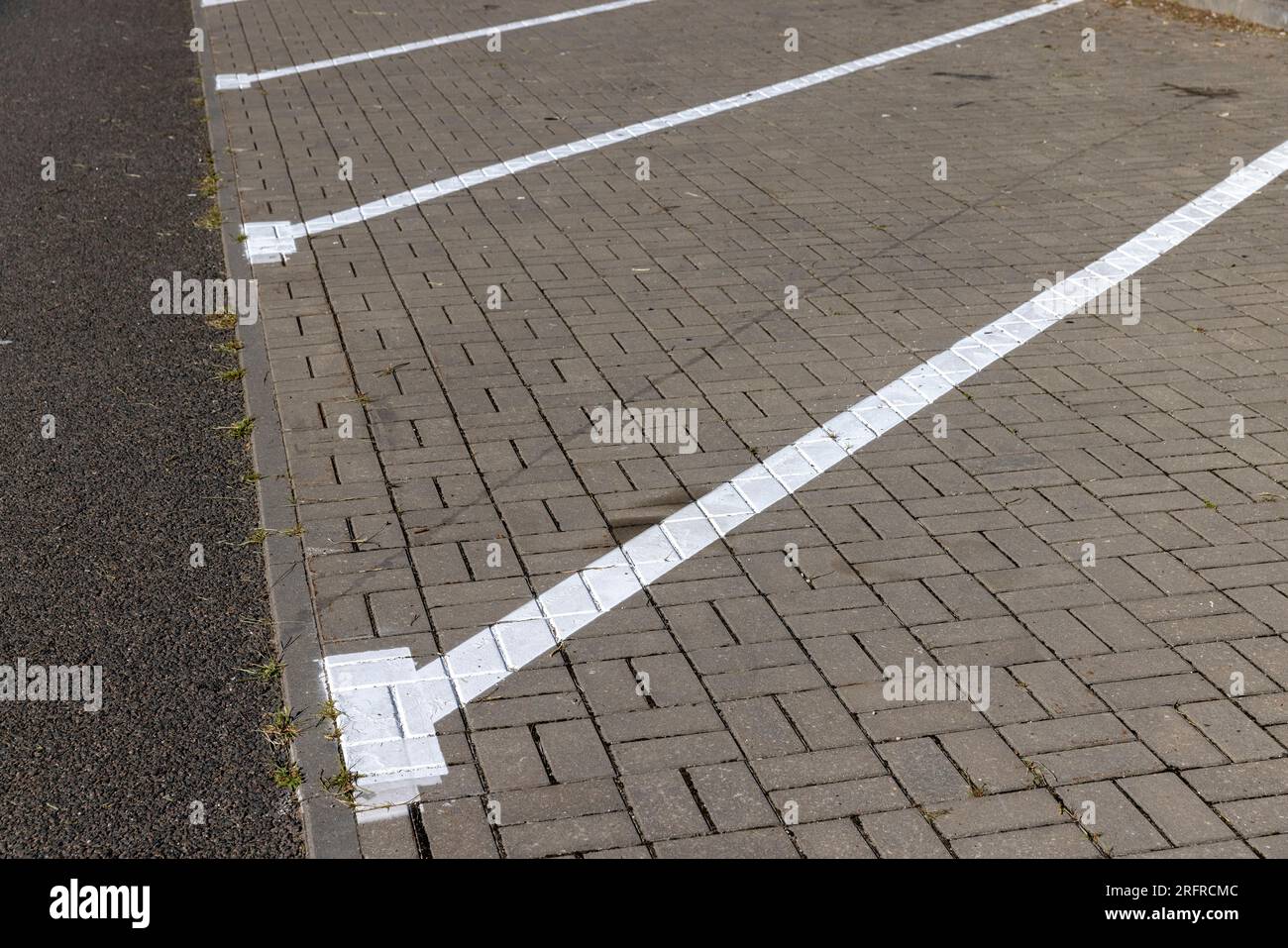 The parking lot is paved with tiles for cars, parking spaces are delimited by white lines Stock Photo