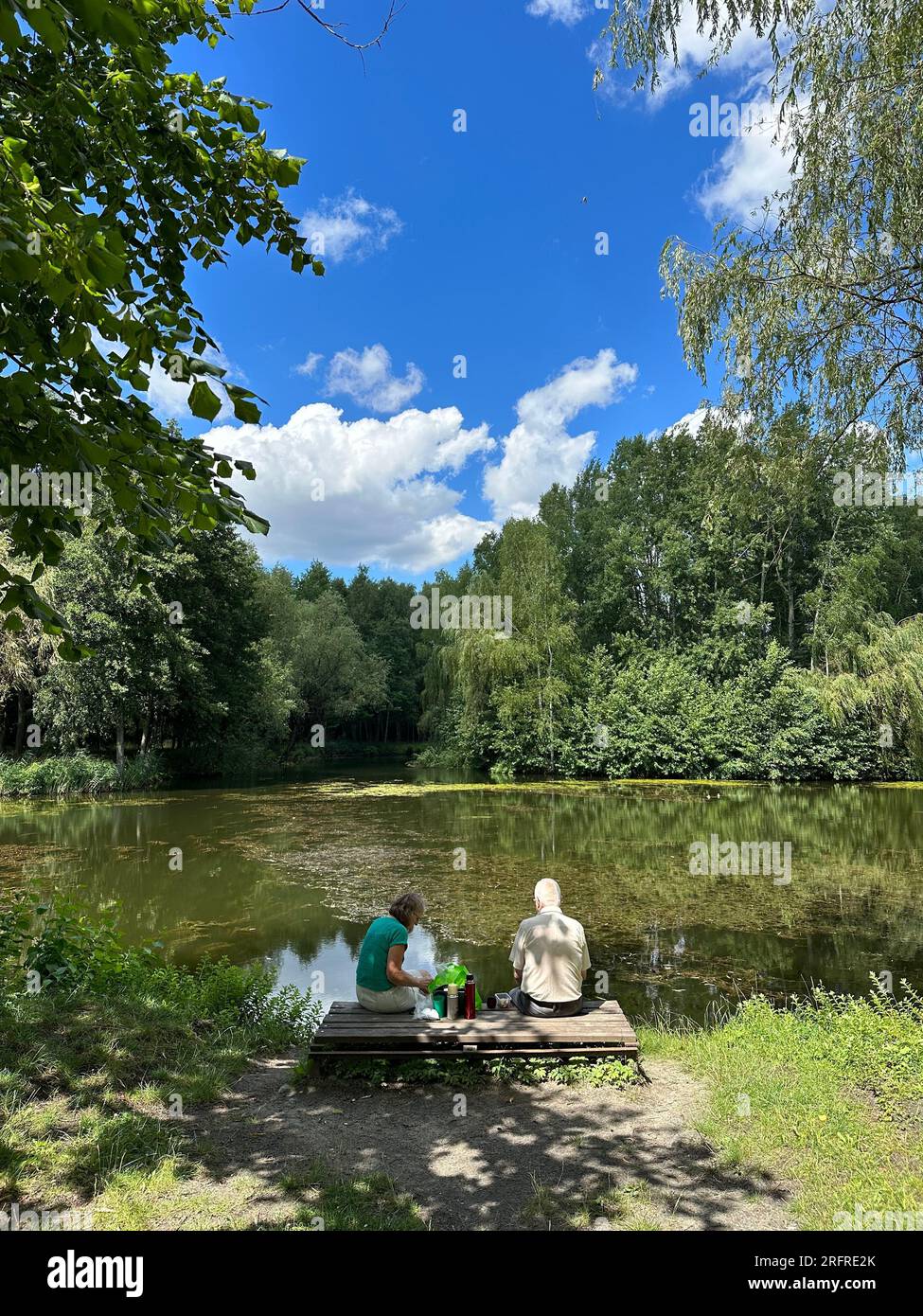 Senior Couple At The Lake Having A Picnic in summer. Old people relaxing on lake in summer Stock Photo