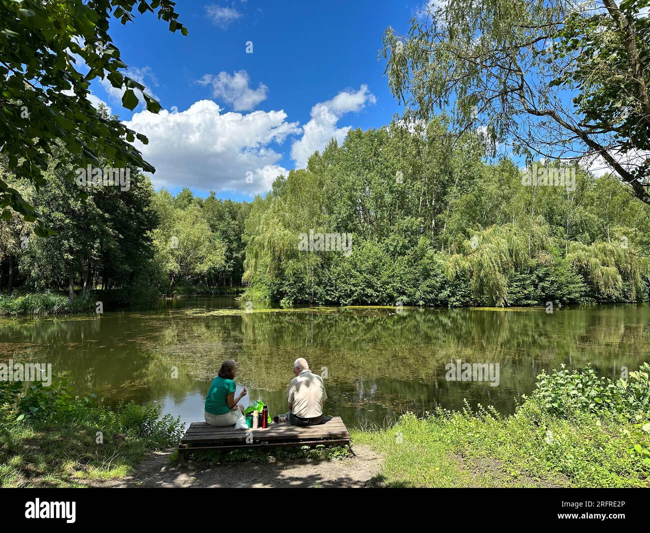 Senior Couple At The Lake Having A Picnic in summer. Old people relaxing on lake in summer Stock Photo