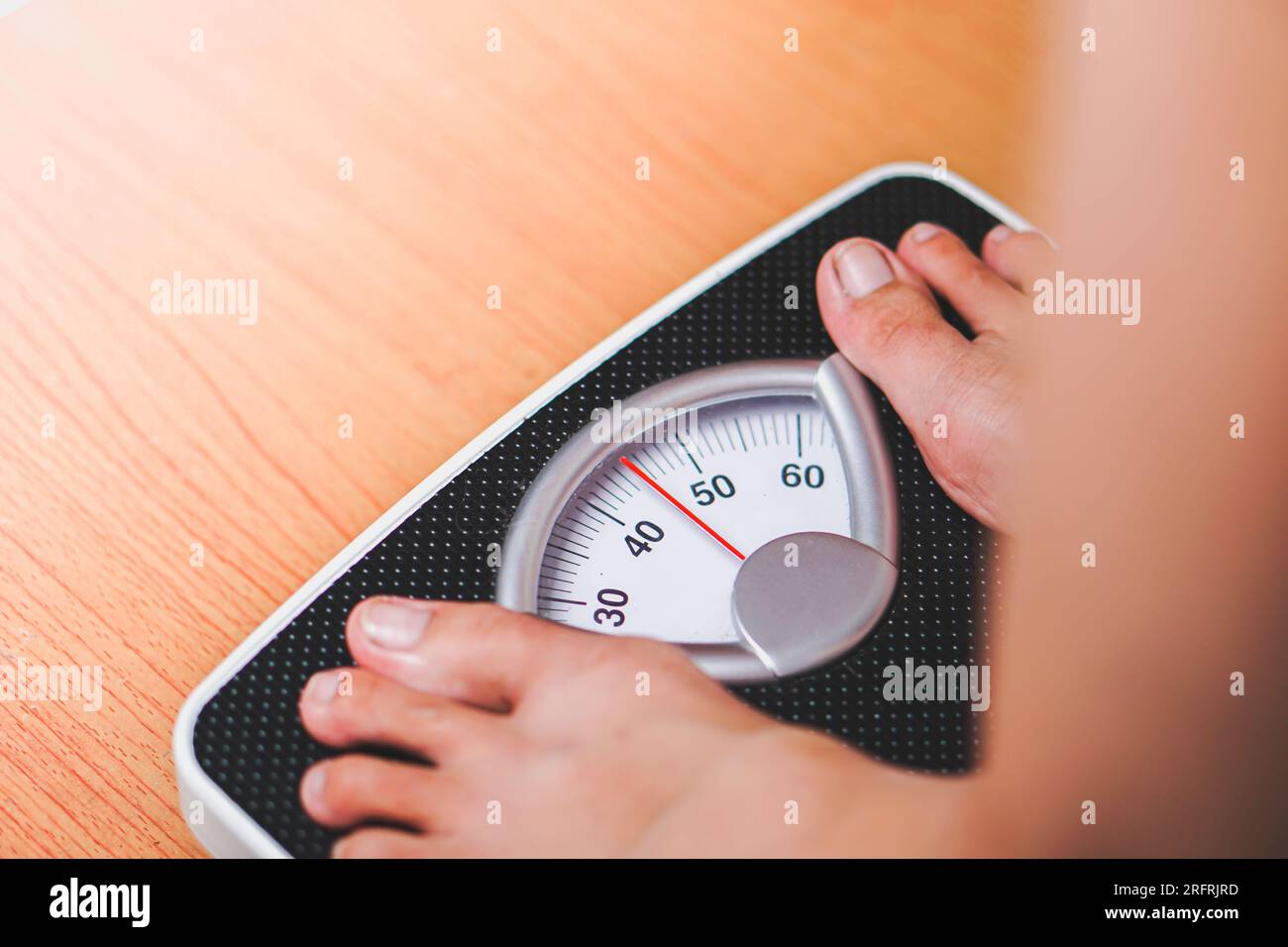 https://c8.alamy.com/comp/2RFRJRD/feet-standing-on-a-black-scale-weighing-machine-with-a-wooden-base-2RFRJRD.jpg