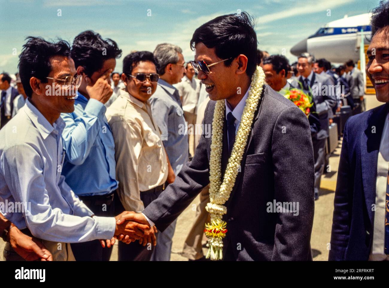Hun Sen with floral garland around his neck, Cambodian political leader & premier of Cambodia, shaking hands with officials at the airport on his return to the government, 1987. Stock Photo