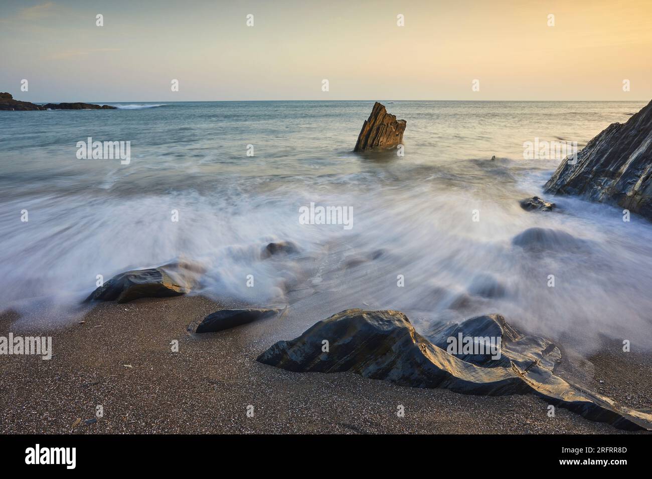 Shoreline rocks washed by waves on a rising tide at sunset; Ayrmer Cove