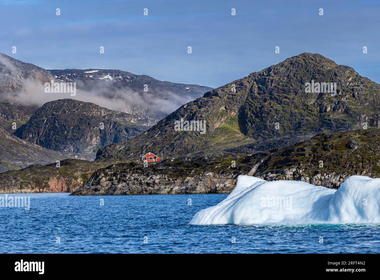 Solitary red house among mountains and icebergs near Rodebay, Kitaa
