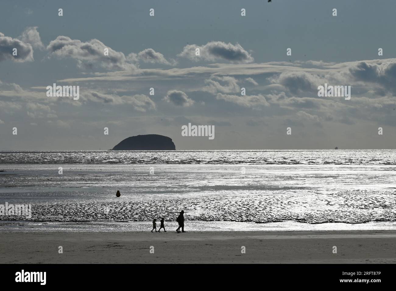 On a warm and windy afternoon people are seen walking against a silvery shimmering low tide at Weston Super Mare . Picture Credit: Robert Timoney/Alamy Live News Stock Photo