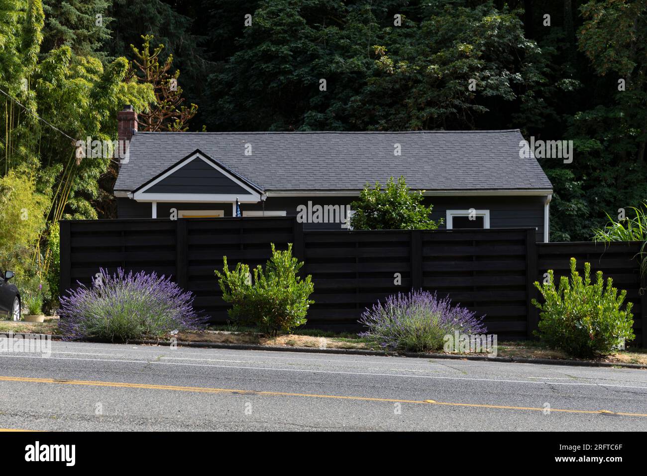 A fence shields a home from busy oncoming traffic along SW Admiral Way in Seattle’s affluent North Admiral neighborhood. Stock Photo