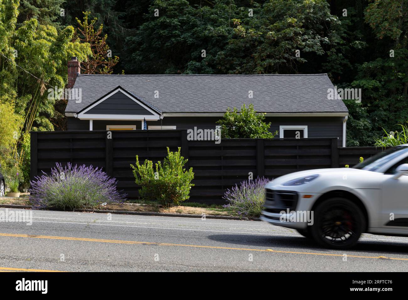 A fence shields a home from busy oncoming traffic along SW Admiral Way in Seattle’s affluent North Admiral neighborhood. Stock Photo
