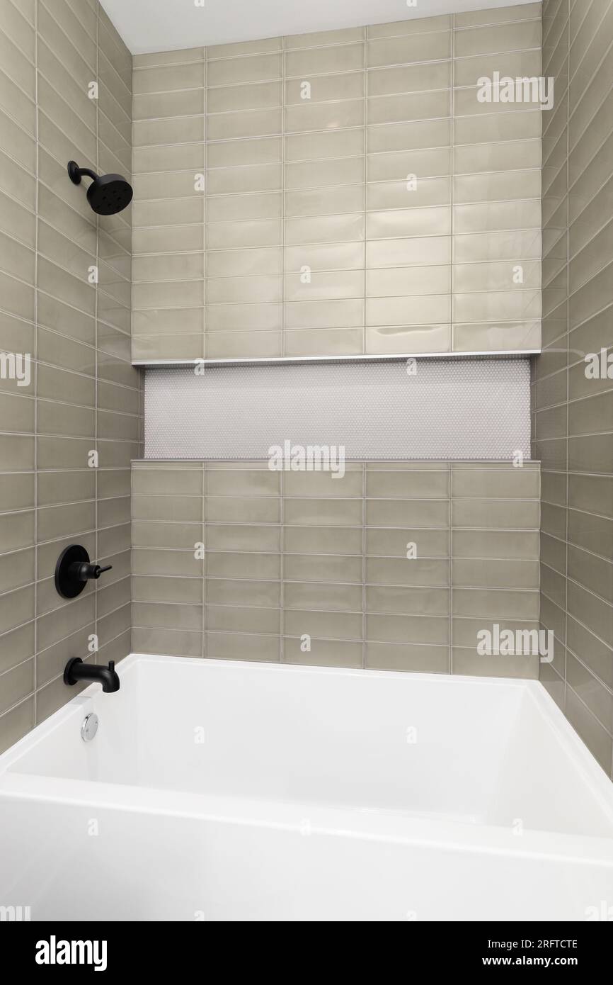 A shower with brown subway tile walls, small hexagon tiles in the shelf
