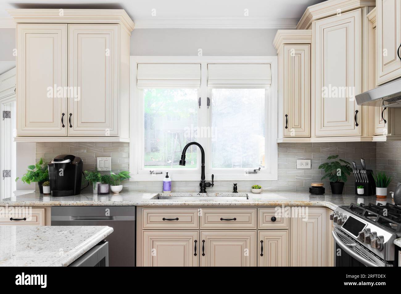 Modern kitchen is white with a black marble countertop. Stove, oven,  cabinets and sink with tap Stock Photo - Alamy