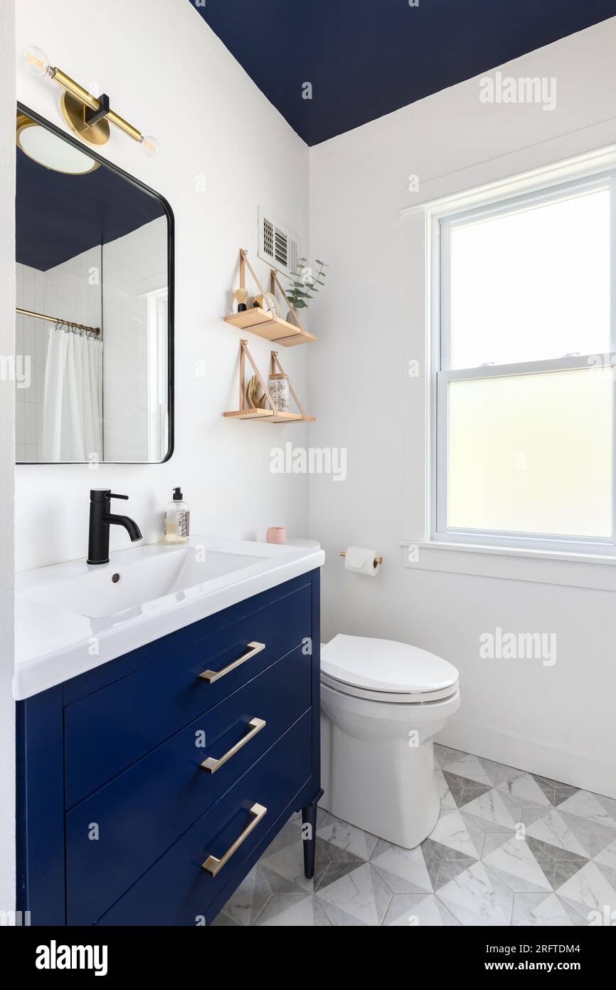 A bathroom with a dark blue cabinet and ceiling, a triangle pattern tile  flooring, and decorations decorations on mounted shelves Stock Photo - Alamy, image size:866x1390
