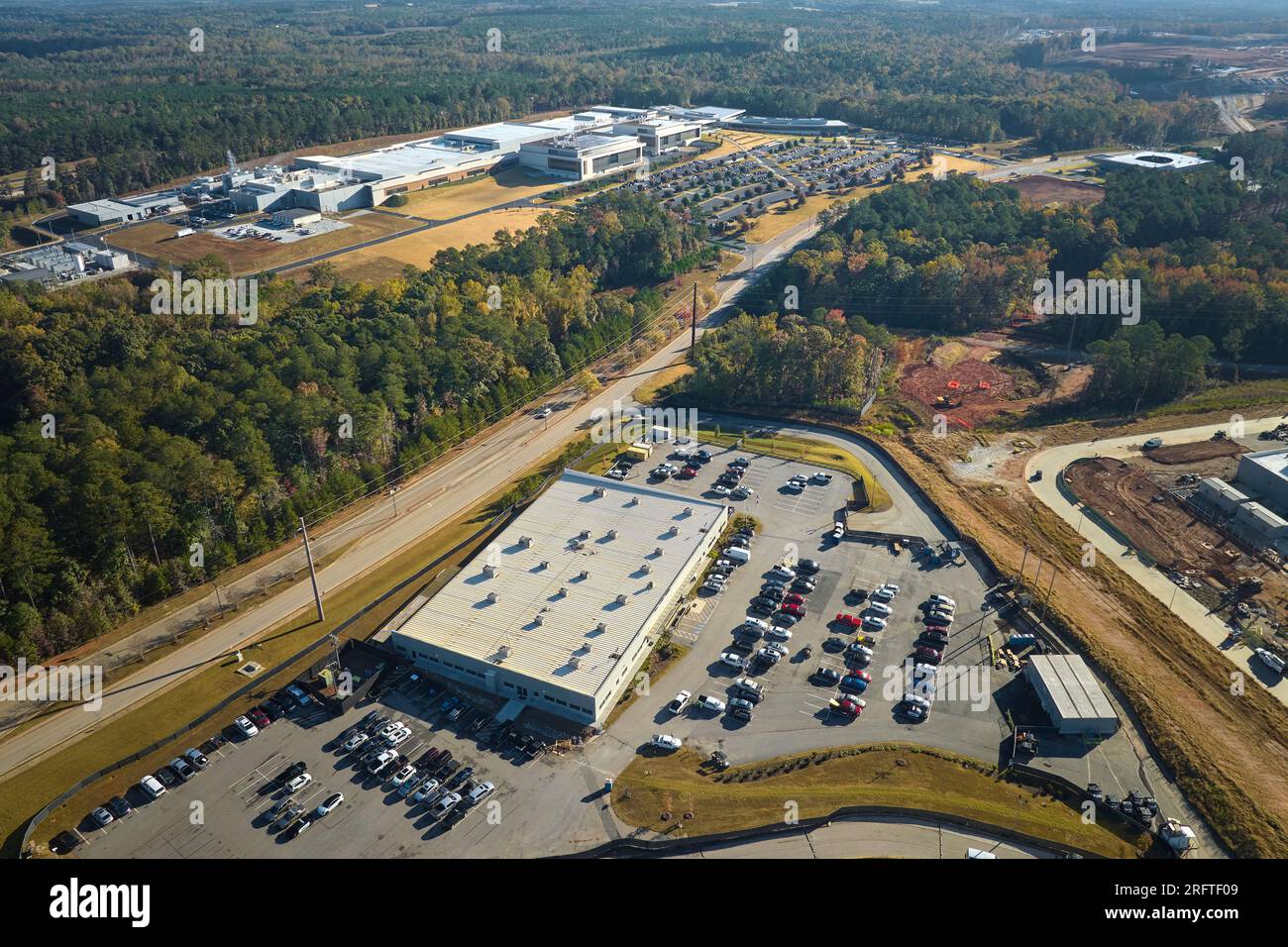 Many associate cars parked on big parking lot in front of industrial