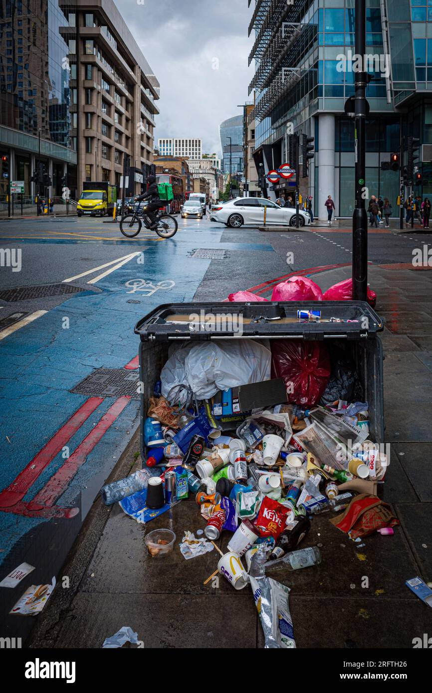 London rubbish - overturned rubbish skip in East London. Overturned rubbish bin London. London street rubbish. Stock Photo
