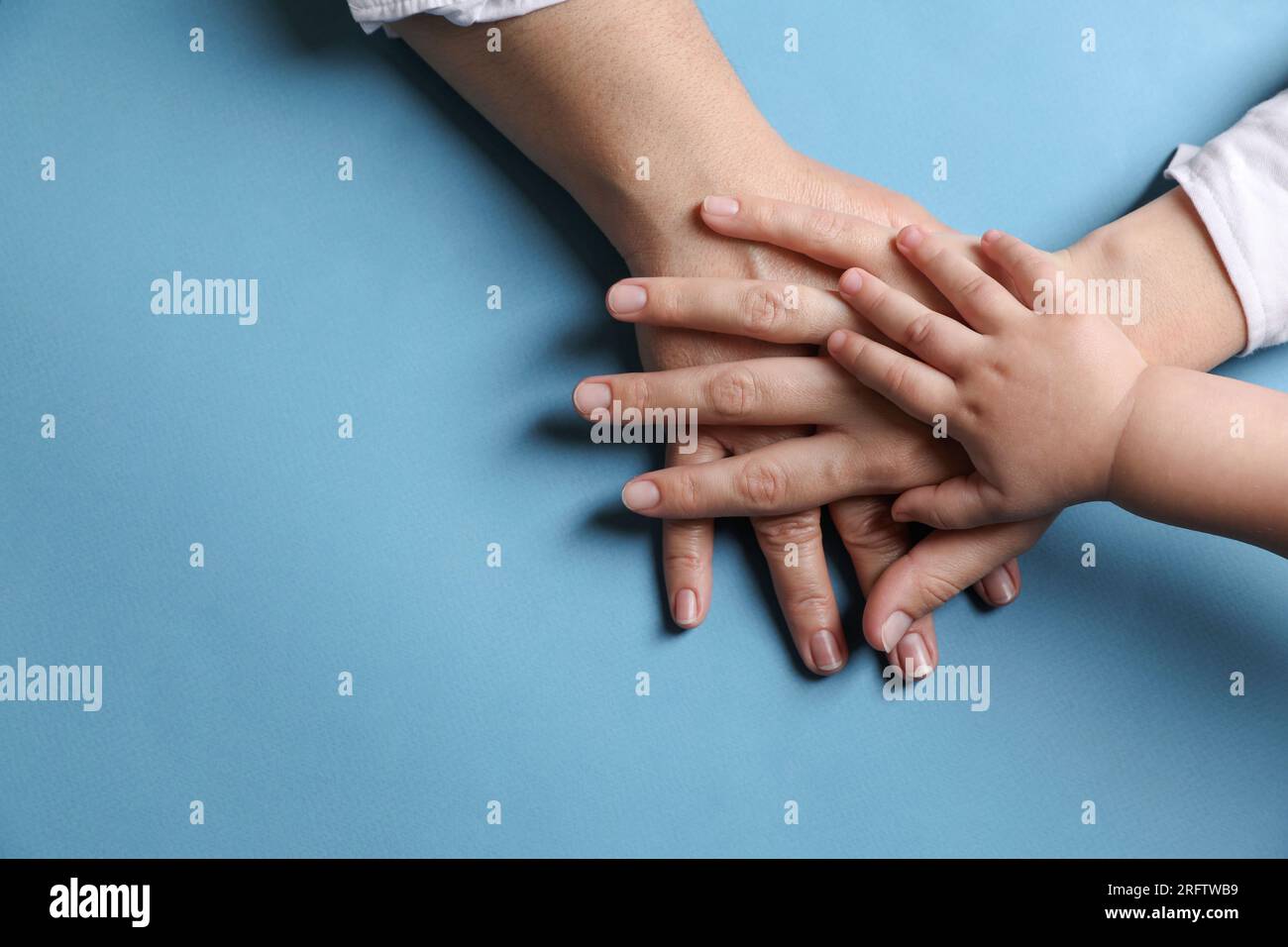 Family holding hands together on light blue background, top view. Space ...