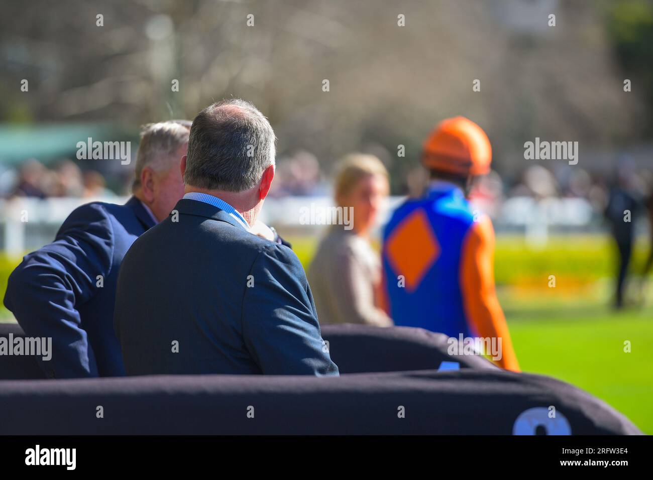 Spectators at the race track watching a jockey getting ready to mount the horse Stock Photo