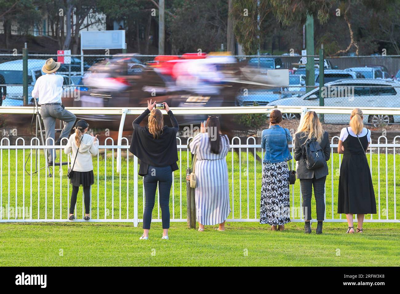 Spectators with mobile phones at the race track watching a horse race start Stock Photo
