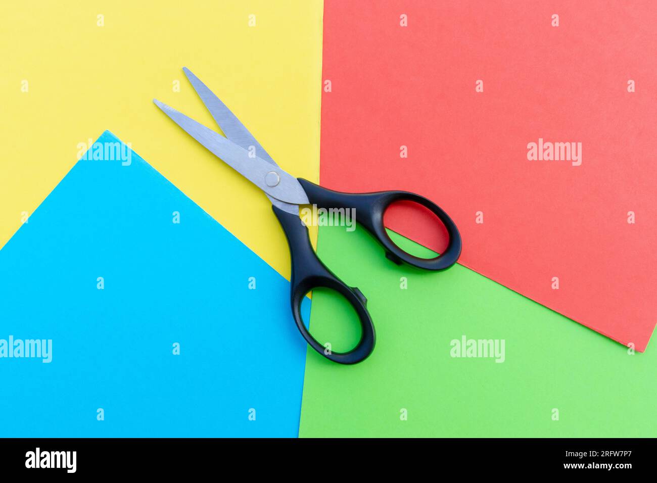 Scissors placed on colored papers, after some edits. Stock Photo