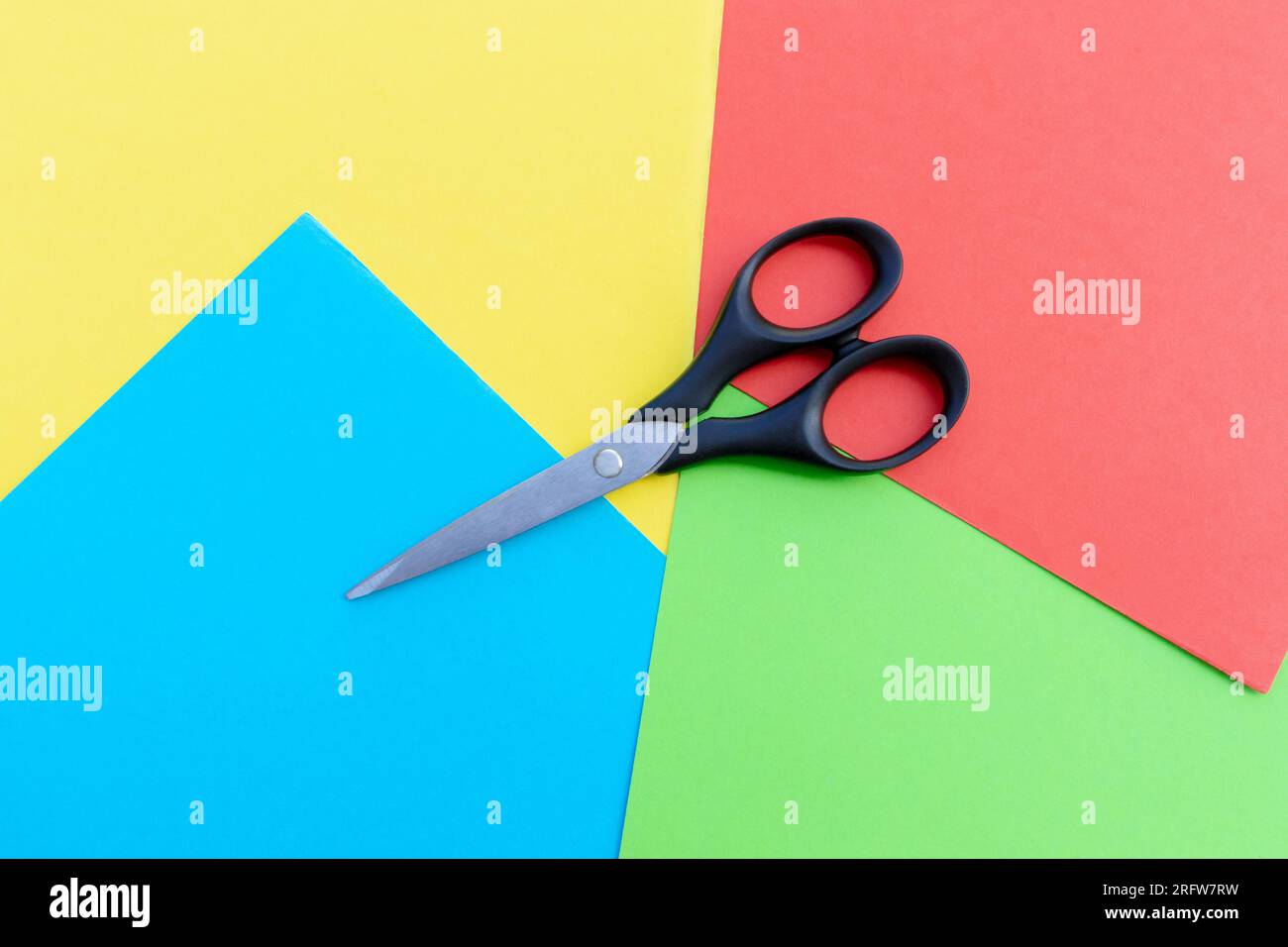 Scissors placed on colored papers, after some edits. Stock Photo