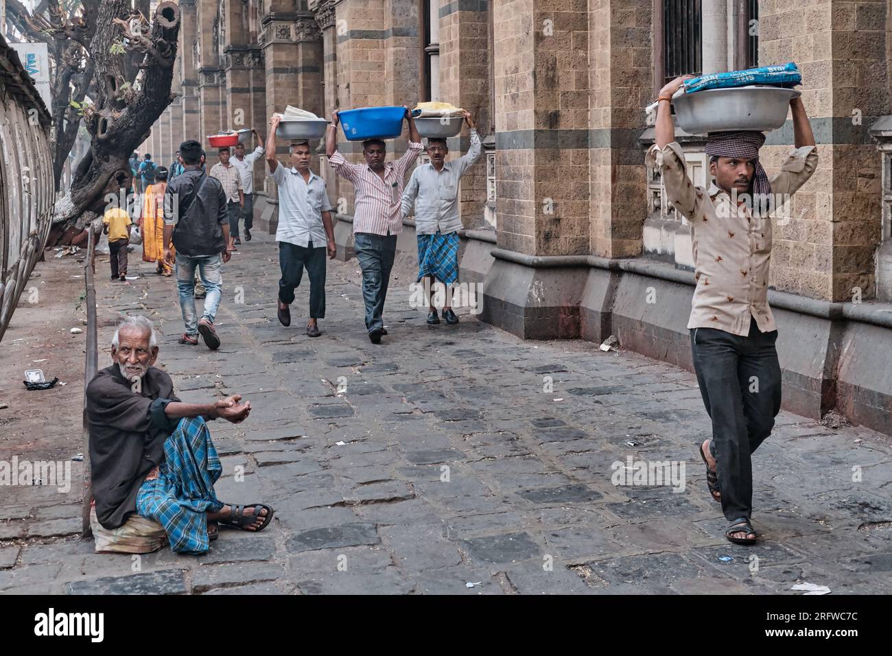 Porters with trayss of fish on their heads, outside Chhatrapati Shivaji Maharaj Terminus (CMST), in Mumbai, India, to forward the trays by train Stock Photo