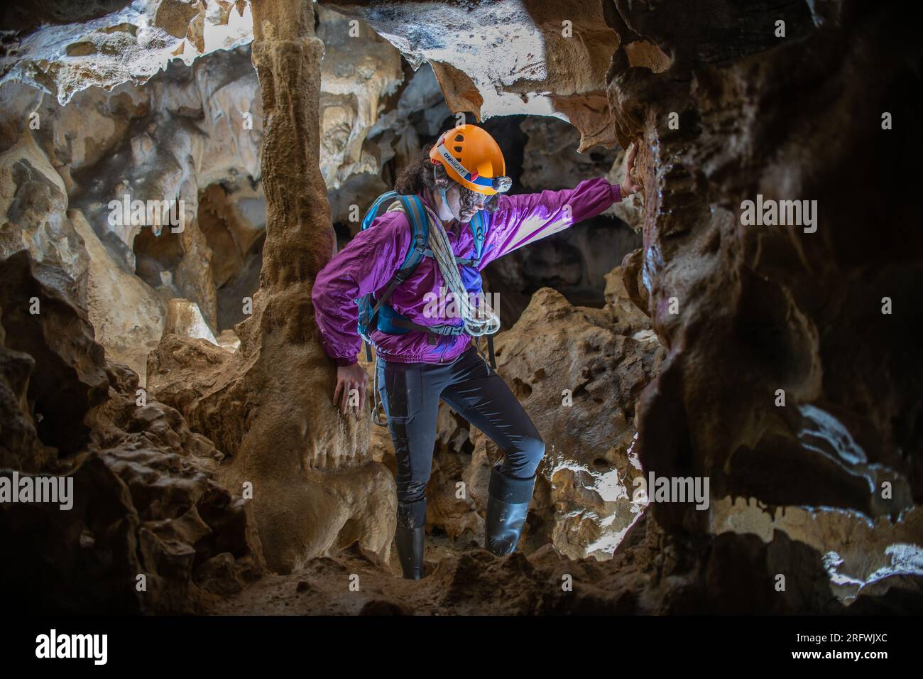 Young woman spelunking inside a cave. Feminism concept. Concept of women's sport. Stock Photo