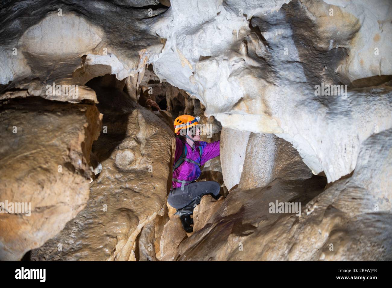 Young woman spelunking inside a cave. Feminism concept. Concept of women's sport. Stock Photo