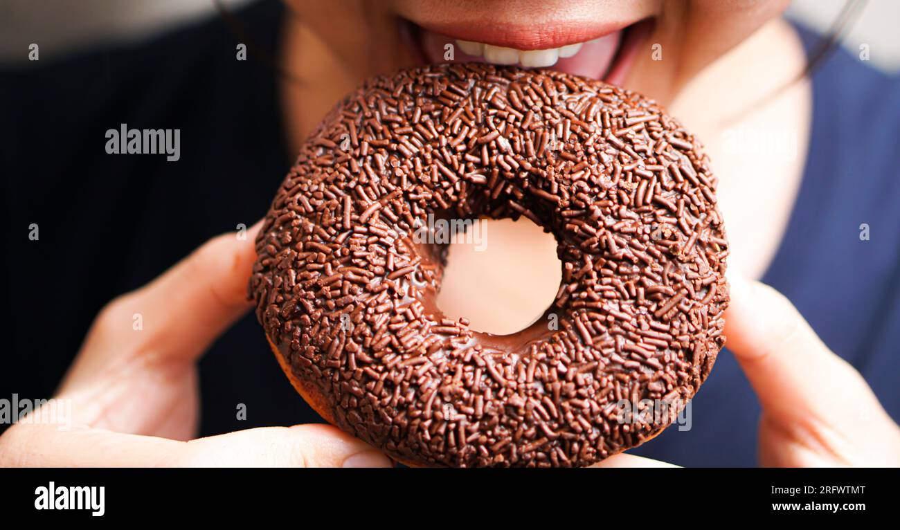 young women eating tasty chocolate donut Stock Photo