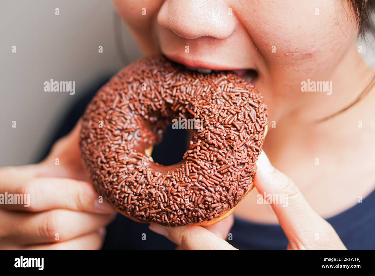 young women eating tasty chocolate donut Stock Photo