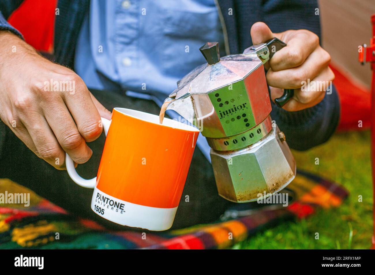 A man pours coffee into a cup from a coffee maker. Stock Photo