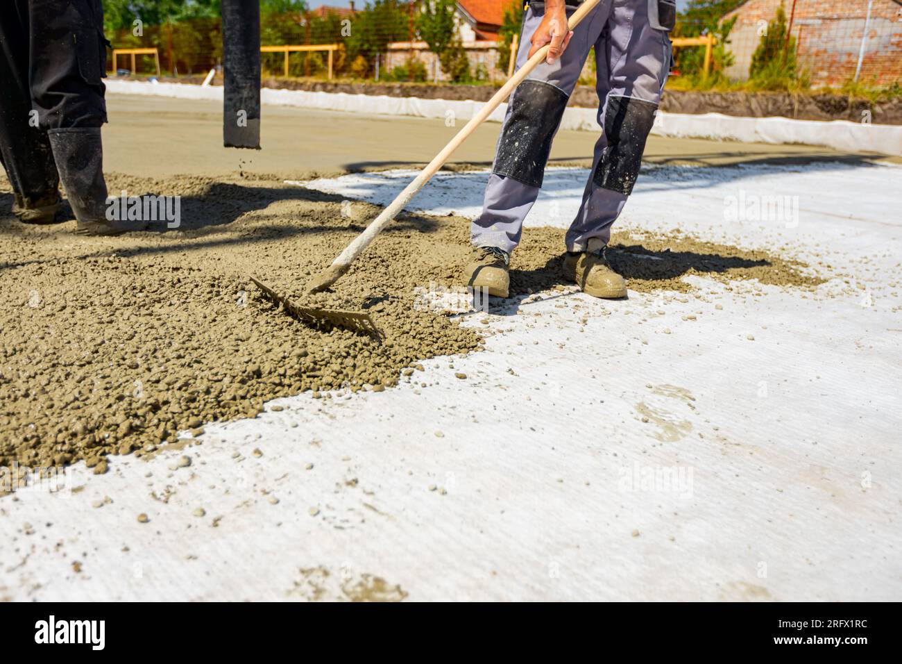 Construction worker, rigger is using rake to spreading, leveling