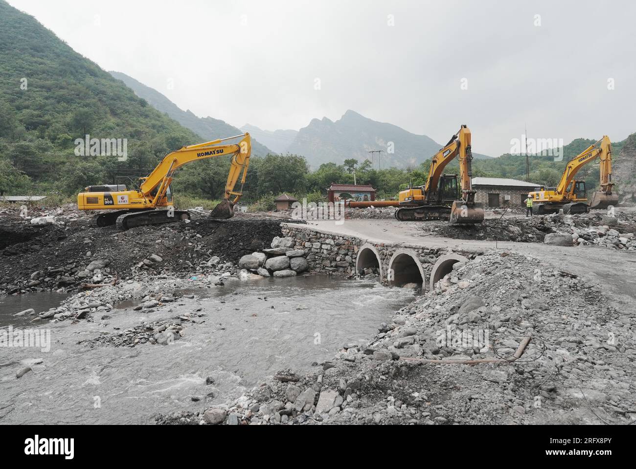 Beijing, China. 6th Aug, 2023. Large machineries carry out restoration work in Shijiaying Town of Fangshan District in Beijing, capital of China, Aug. 6, 2023. Beijing has been speeding up the restoration of roads damaged in flood-hit areas, to assist with rescue and relief efforts. Credit: Ju Huanzong/Xinhua/Alamy Live News Stock Photo