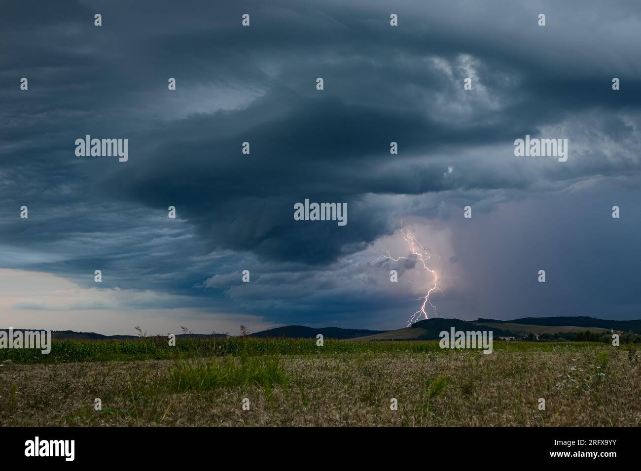 Lightning strikes down from a dramatic looking storm cloud at dusk ...