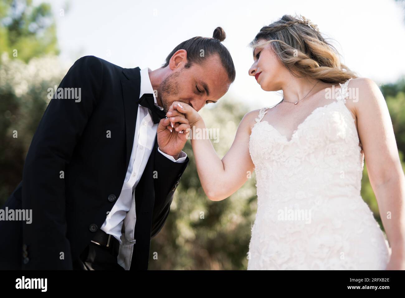 Ein charmanter Bräutigam küsst die Hand der Braut Stock Photo