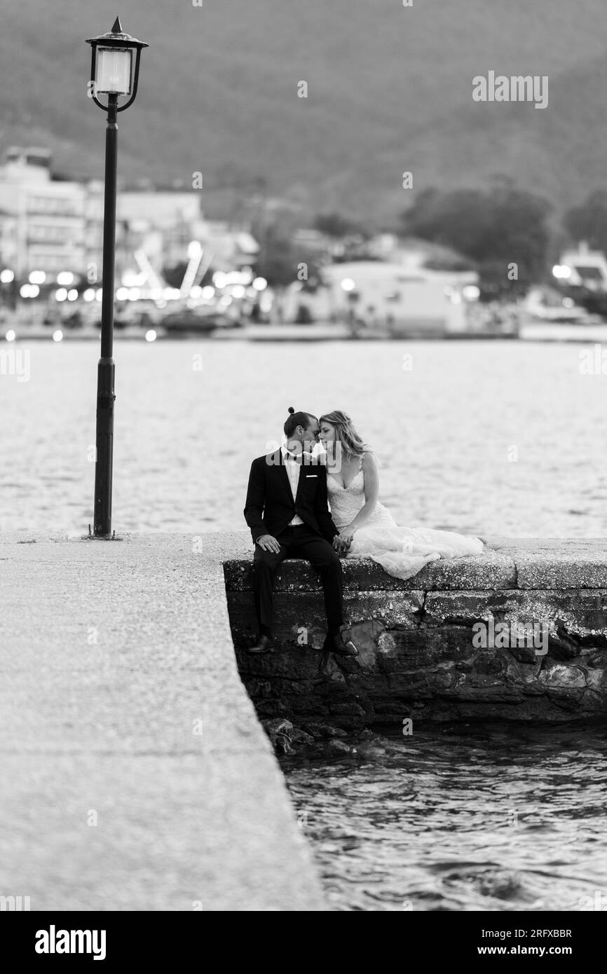 Ein Brautpaar sitzt am Hafen von Thasso und wartet auf die Welle Stock Photo