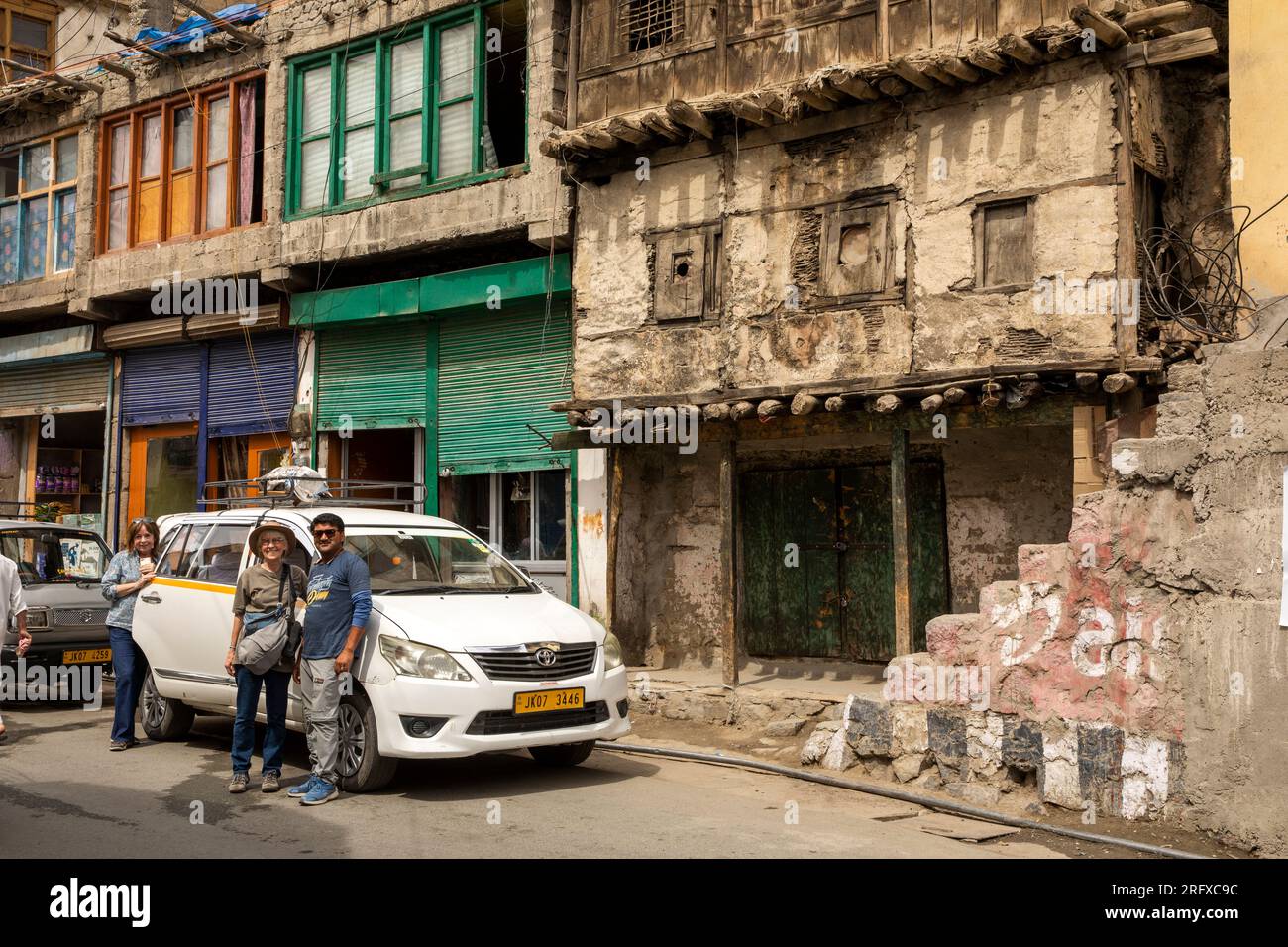 India, Jammu & Kashmir, Kargil, bazaar, tourists with driver below historic old building Stock Photo