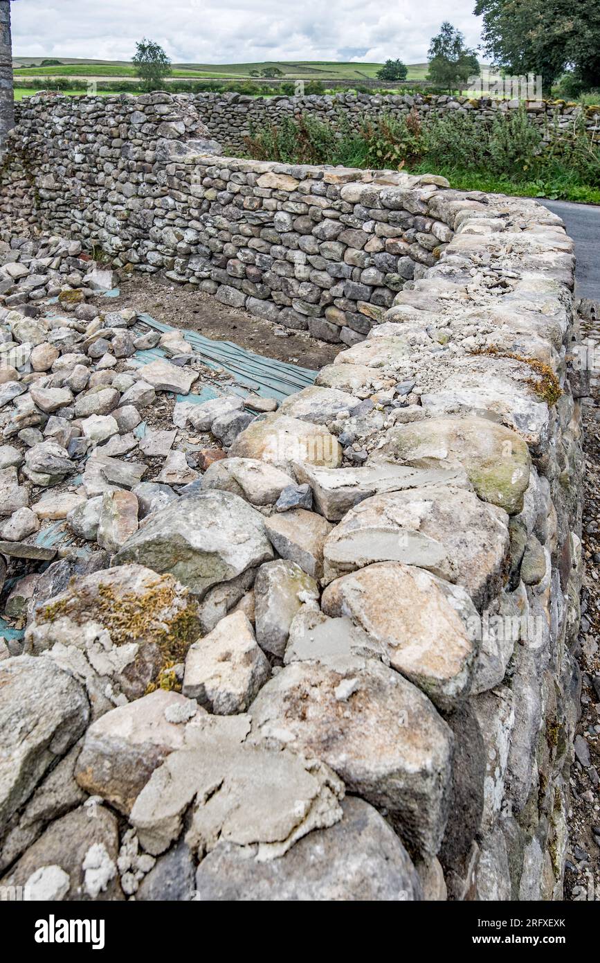 Restoration & rebuild of a stone wall in Long Preston adjacent to  former boys school (now a storage/garage type area). Good quality craftsman waller. Stock Photo