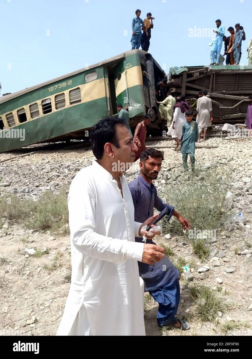 Islamabad. 6th Aug, 2023. This photo taken with a mobile phone shows people walking past derailed compartments of a passenger train in the Sanghar district of Pakistan's southern Sindh province on Aug. 6, 2023. At least 22 people were killed and over 50 others injured on Sunday after a passenger train derailed in the Sanghar district of Pakistan's southern Sindh province, local police said. Credit: Str/Xinhua/Alamy Live News Stock Photo