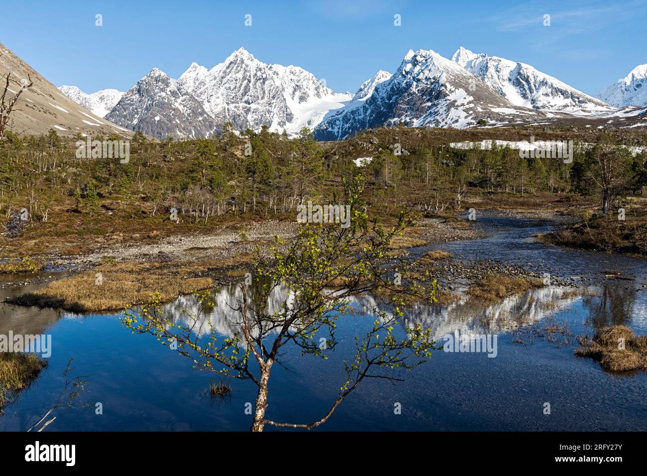 At the beginning of the hike to Blåisvatnet, the Blue Lake. Snow-capped mountains are reflected in the water of the river. Lyngen Alps, Lyngen, Norway Stock Photo